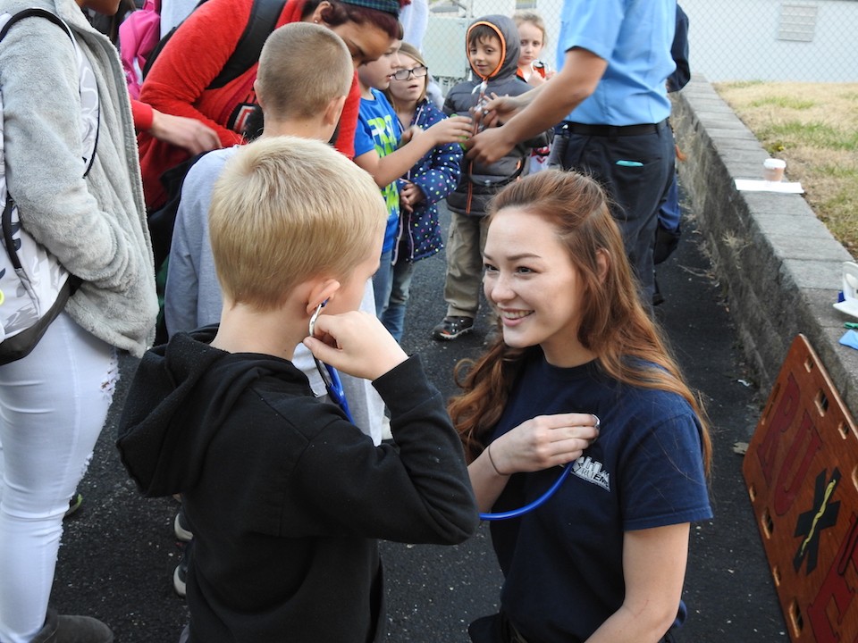 Hailey Laird, right, lets a child use a stethoscope to hear her heart beat.