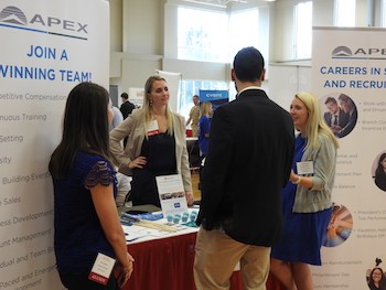 Alumni Erin Upton, left, and Alyssa Wohlleben, second from left, speak with a student about their company. 