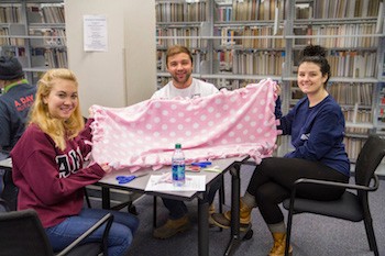 Nate Ogden, center, helps display one of the blankets made for Project Linus.