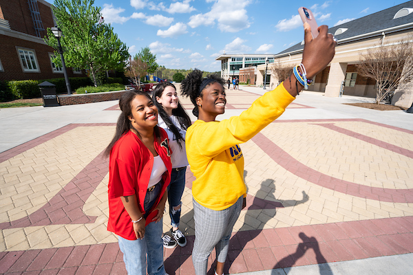 Three students pose outside for a selfie. 