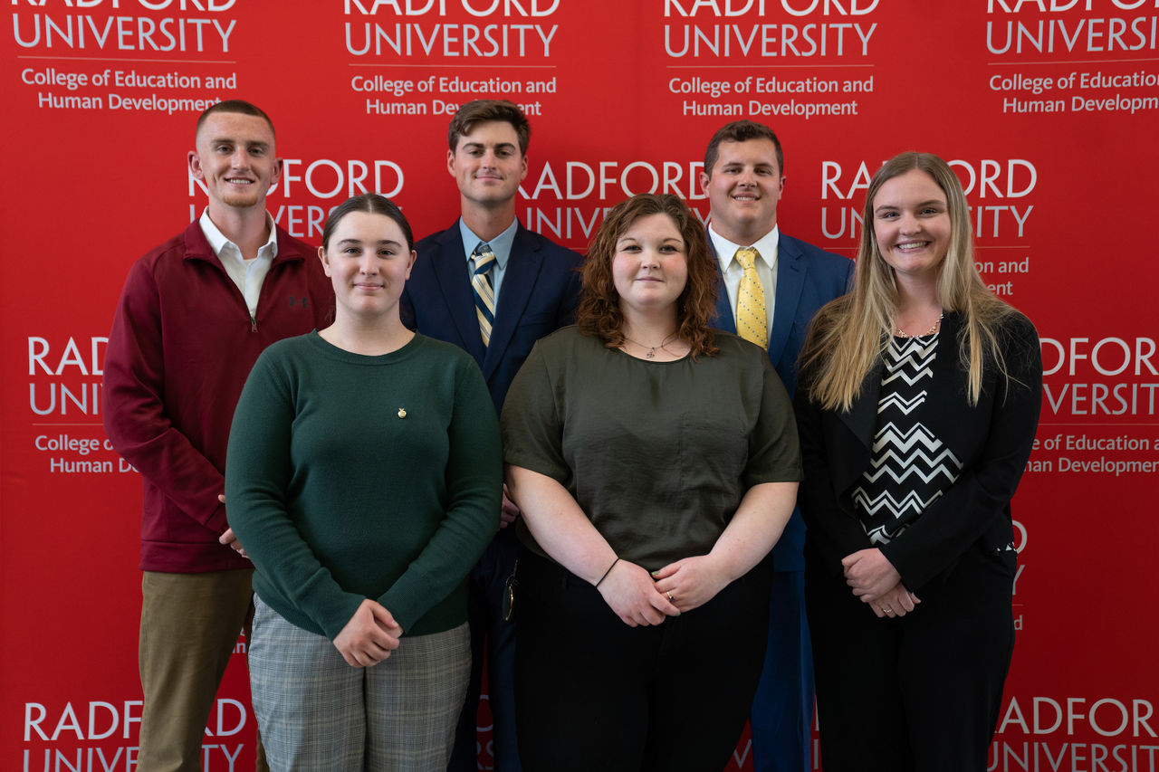 The six Strong Scholars stand in front of a red Radford University backdrop.