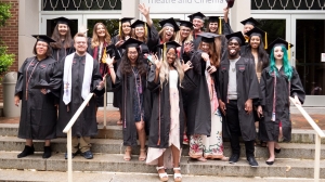 Graduating graphic design students cheer for the camera outside of Porterfield Hall. 