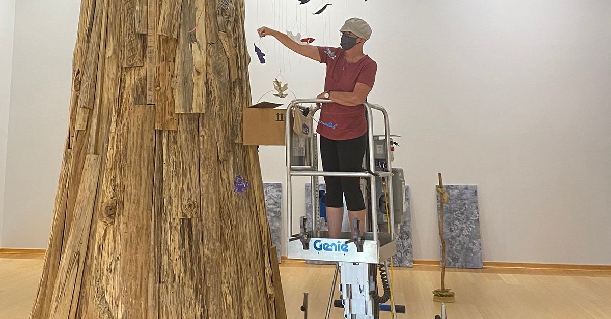 Artist Jennifer L. Hand installs hanging leaves at the "Leaves of the Tree" exhibit set to open September 2020