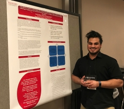 Radford student David Blanco stands beside poster at music therapy conference