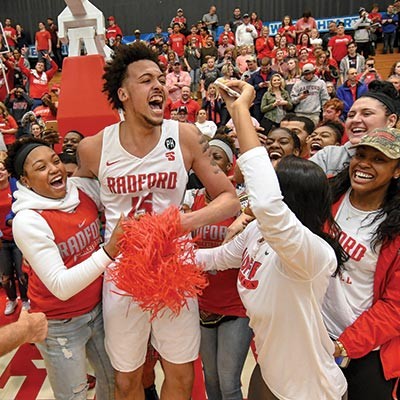 The Radford University men's basketball team celebrates after a win in the NCAA