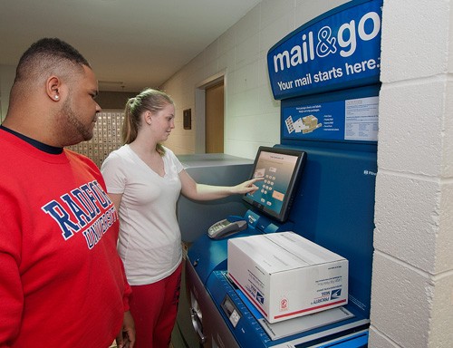 Emily Gerding and Ezell Johnson weigh a package on the new Mail & Go kiosk at the RU Post Office.