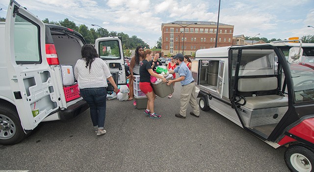 Members of the RU Swim Club and a member of the RU Facilities division move items onto a facilities buggy to be moved to the residence halls.
