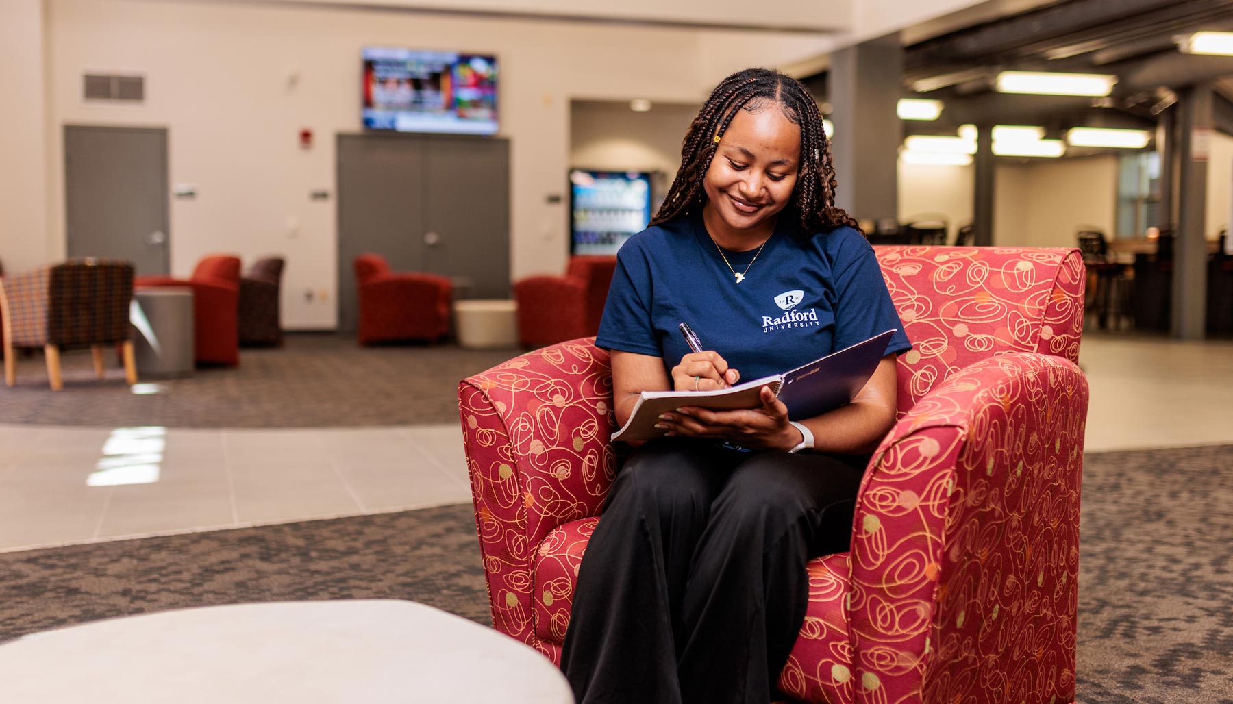 student in chair with notepad writing