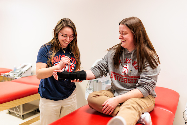 Two students in Radford's athletic training program smile as they collaborate on a classroom exercise.