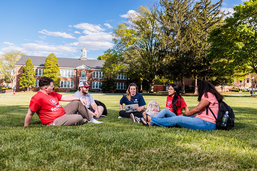 Students sitting on campus lawn in front of Whitt Hall.