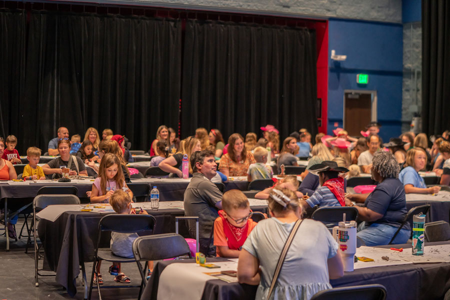 Group sitting at tables in black box theater.