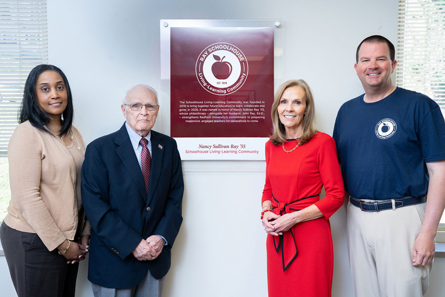 Administration and family standing at a sign that reads Nancy Sullivan Ray Living Learning Community