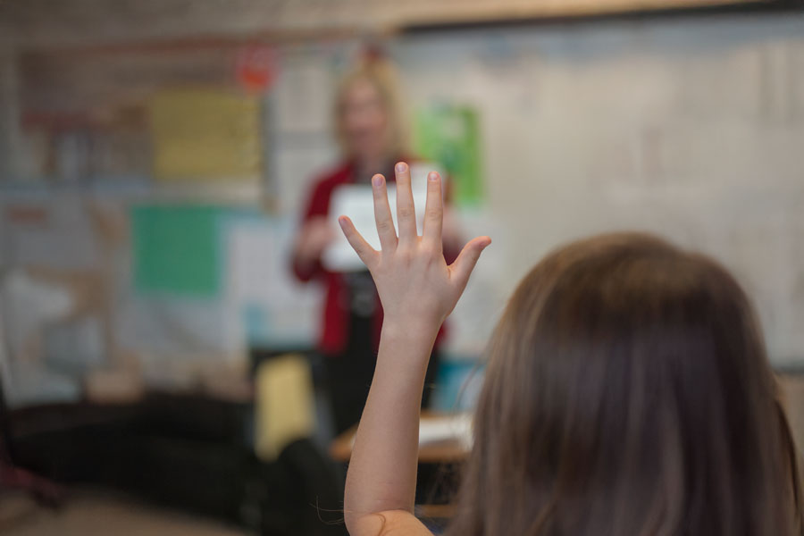 student raising their hand in a classroom