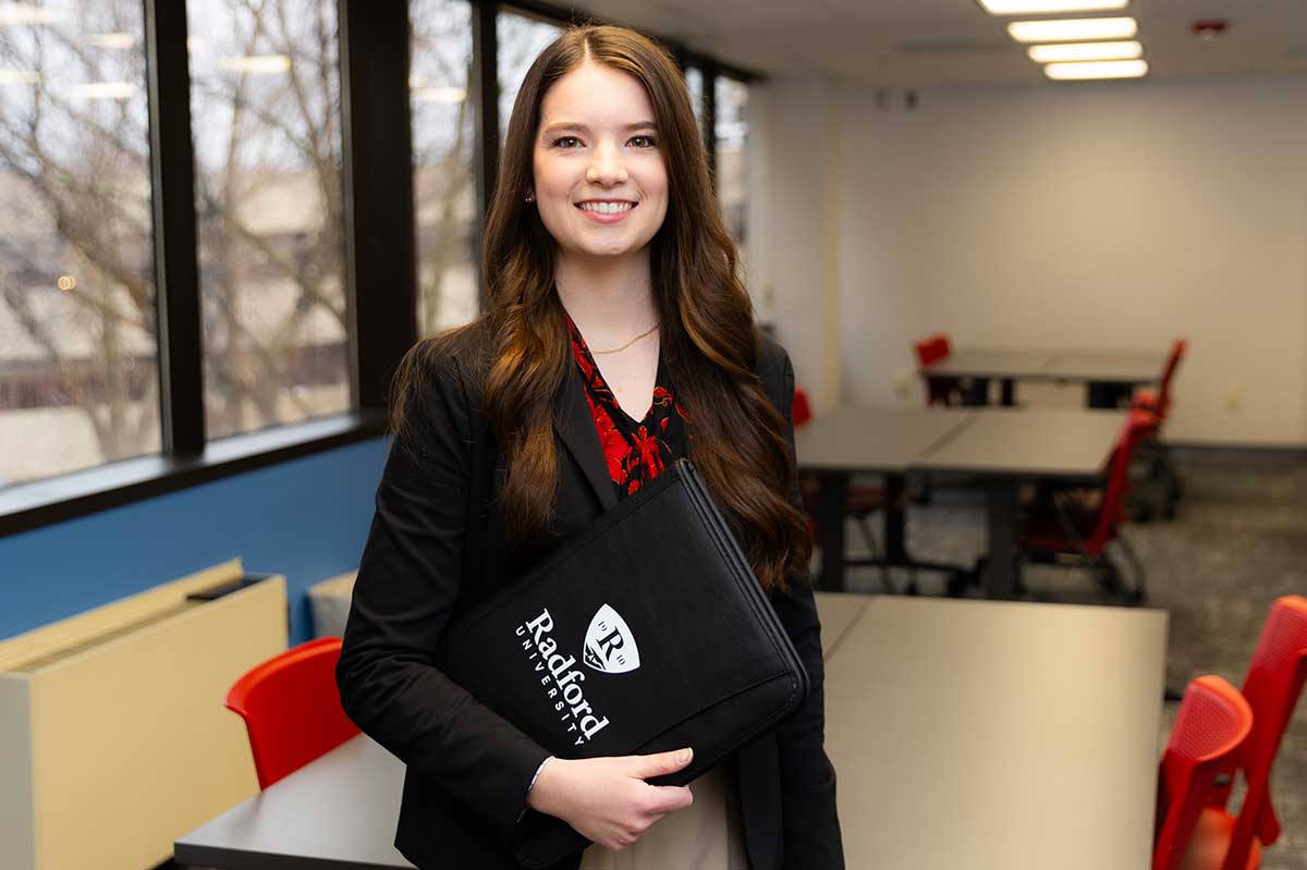 Student in business attire holding padfolio in professional setting