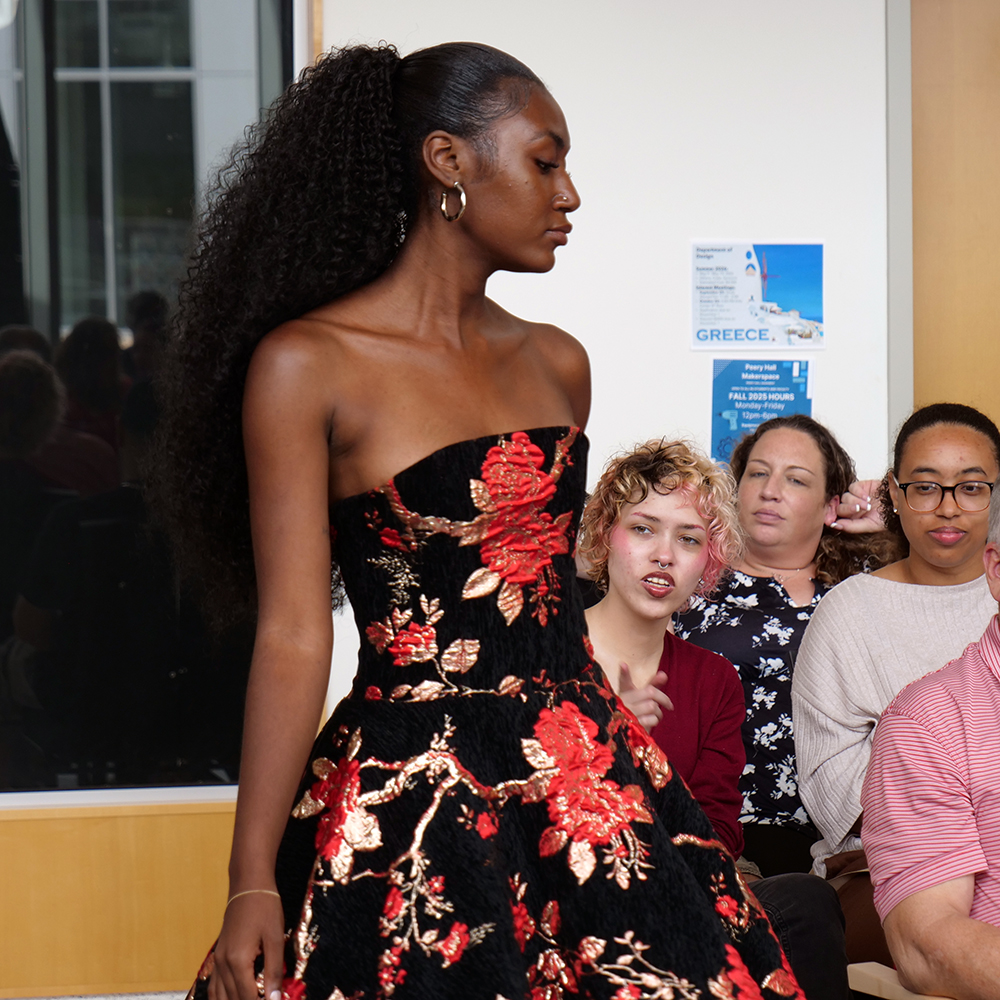 Fashion model in black dress with dramatic red floral pattern.