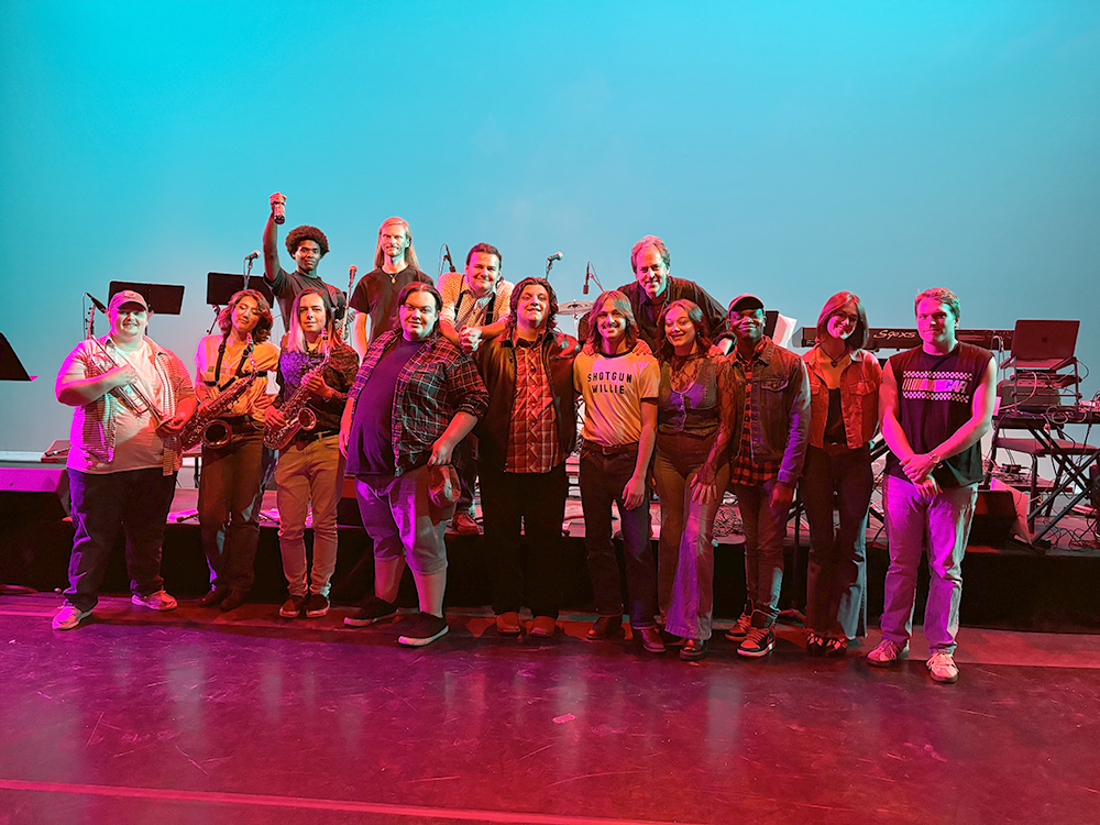 The Commercial Music Ensemble posing on stage with director David Rivers.